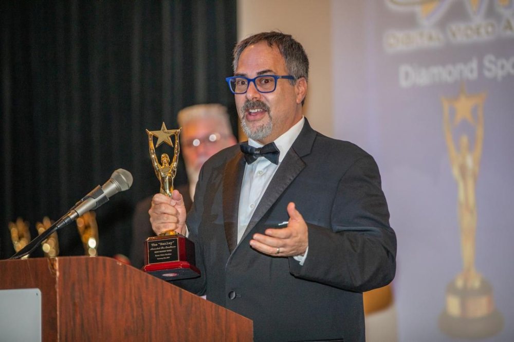 Jason in a tuxedo accepting a video production award