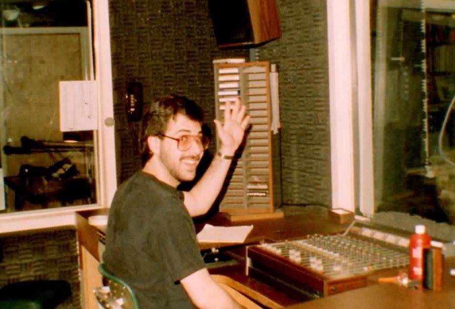 A young Jason waving from the control board at his college radio station, WRHU